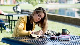 Female student does homework on a picnic table